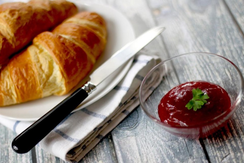 Croissants on a plate with jam and a butter knife
