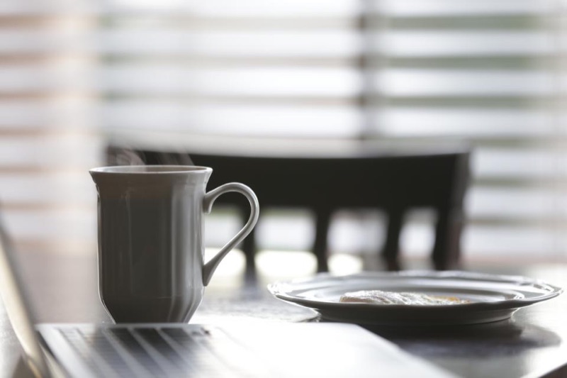 Coffee mug on a table beside a sunny window